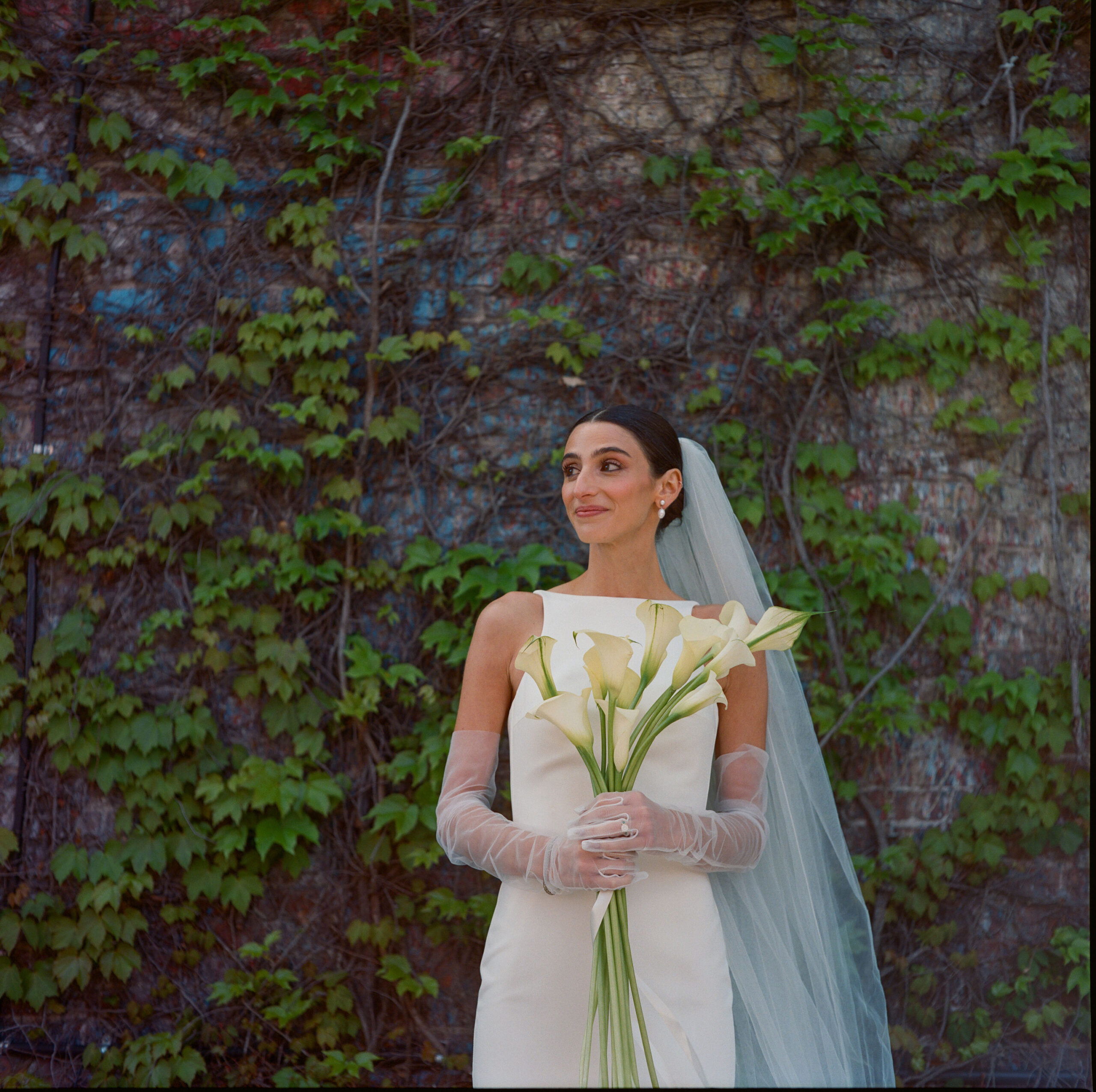 bride with callalilies against ivy wall nyc wedding shot on medium format film